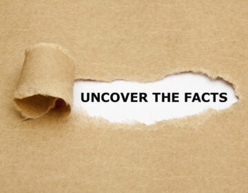 Uncover The Facts appearing behind torn brown paper.
** Note: Shallow depth of field