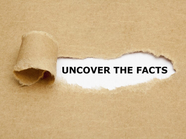 Uncover The Facts appearing behind torn brown paper.
** Note: Shallow depth of field