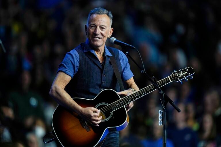 Springsteen And Trump Bruce Springsteen performing on stage with a guitar