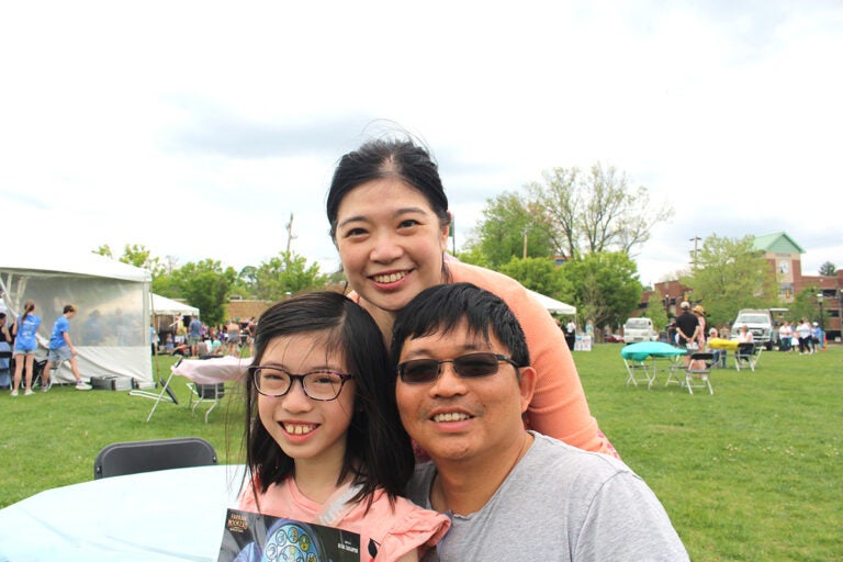 Olivia, 11, left, poses with her parents, Laisand Kan, middle, and Jin Mei, right. Olivia likes mystery books and purchased three new ones at the Bucks County Book Festival on May 3, 2025. (Emily Neil/WHYY)