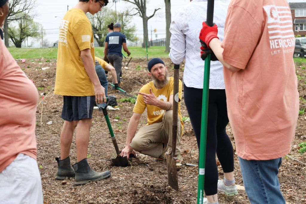 Michael Peterman shows Heroic Gardens volunteers how to dig holes