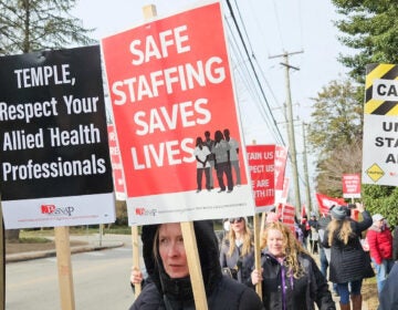 Nurses and technicians in Philadelphia hold signs regarding complaints over staffing