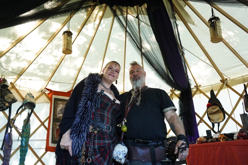 A man and a woman pose in medieval garb with handcrafted leather items