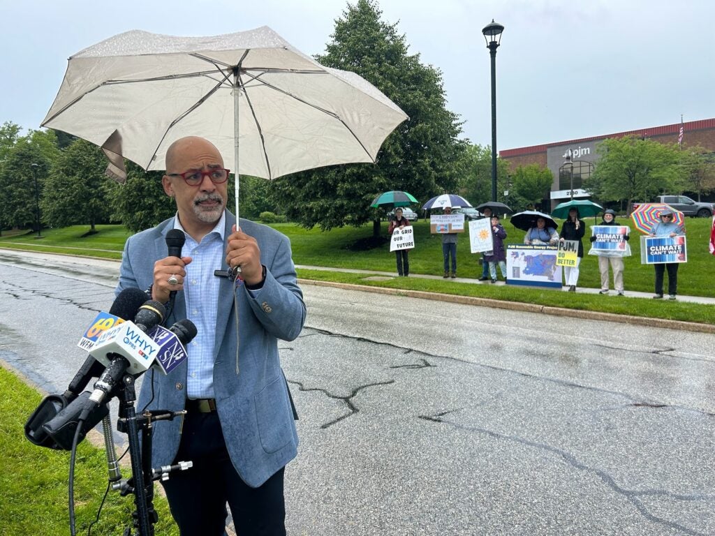 Chris Rabb speaking into microphones at the outdoor rally