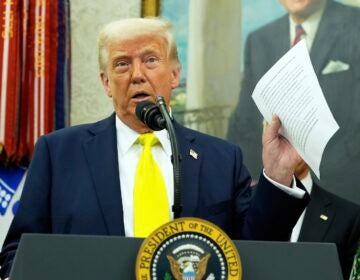 President Donald Trump holds a document with notes about Kilmar Abrego Garcia as he speaks with reporters in the Oval Office of the White House, April 18, 2025, in Washington.