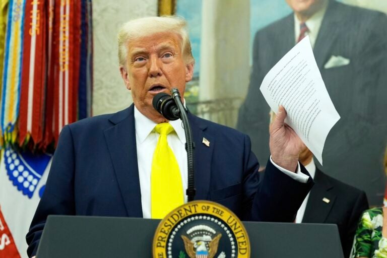 Trump 100 Days President Donald Trump holds a document with notes about Kilmar Abrego Garcia as he speaks with reporters in the Oval Office of the White House, April 18, 2025, in Washington.