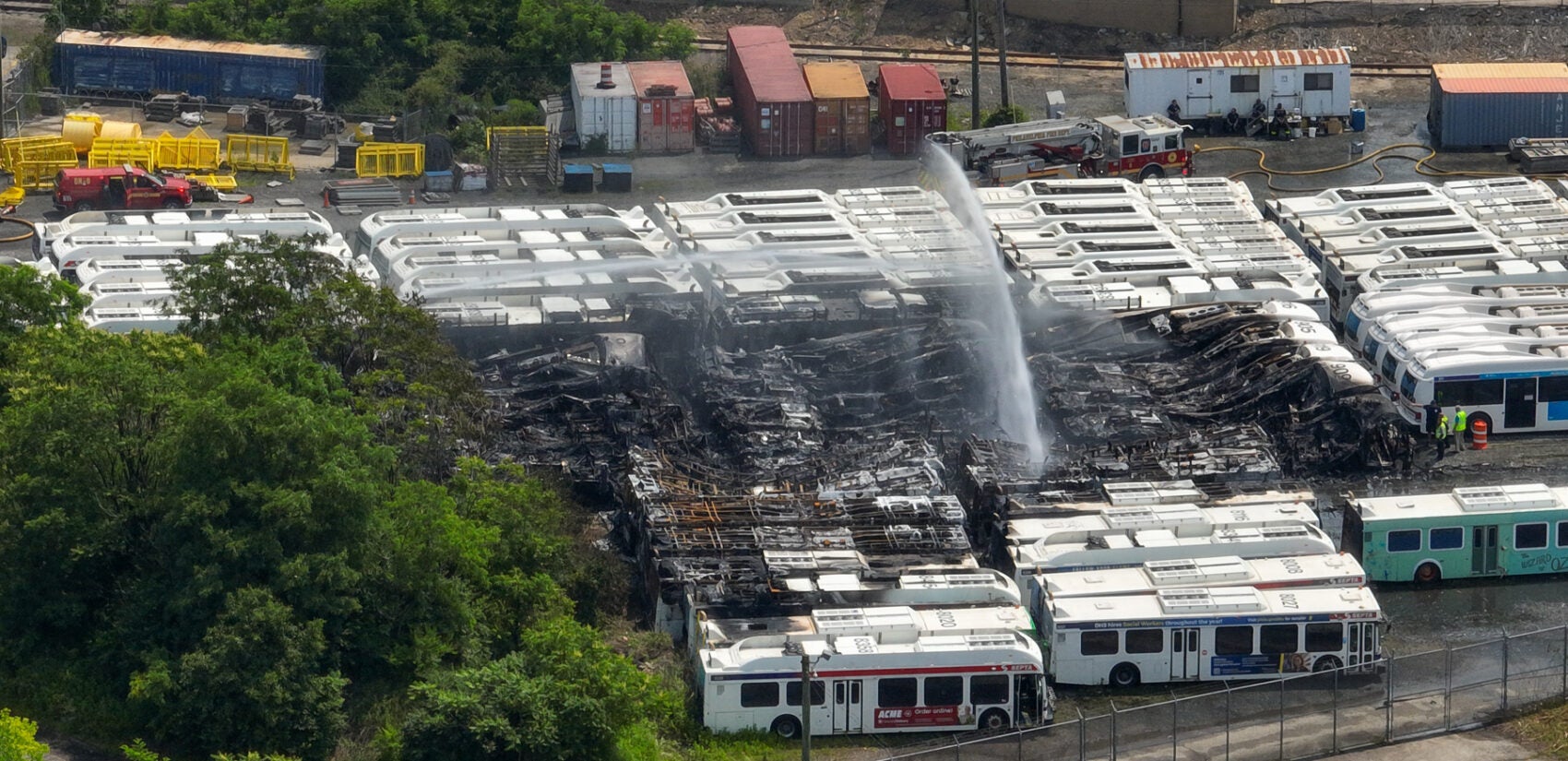 an aerial view of water being sprayed over the burned SEPTA buses