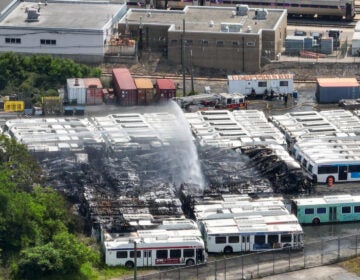 an aerial view of water being sprayed over the burned SEPTA buses