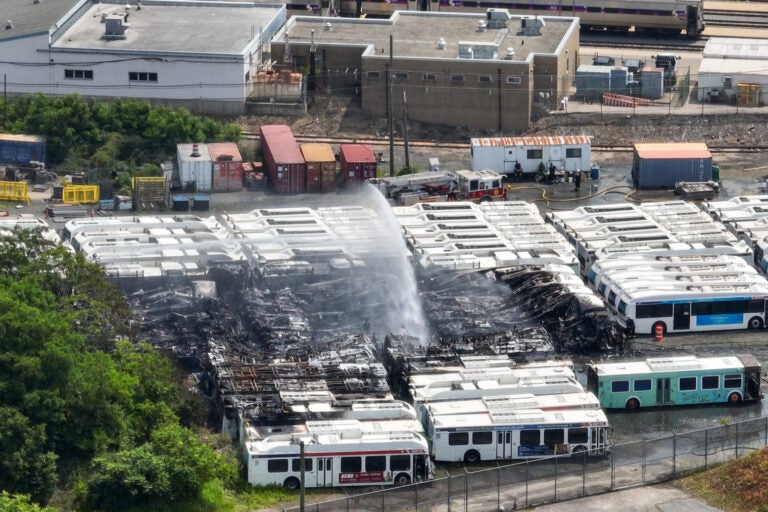 an aerial view of water being sprayed over the burned SEPTA buses