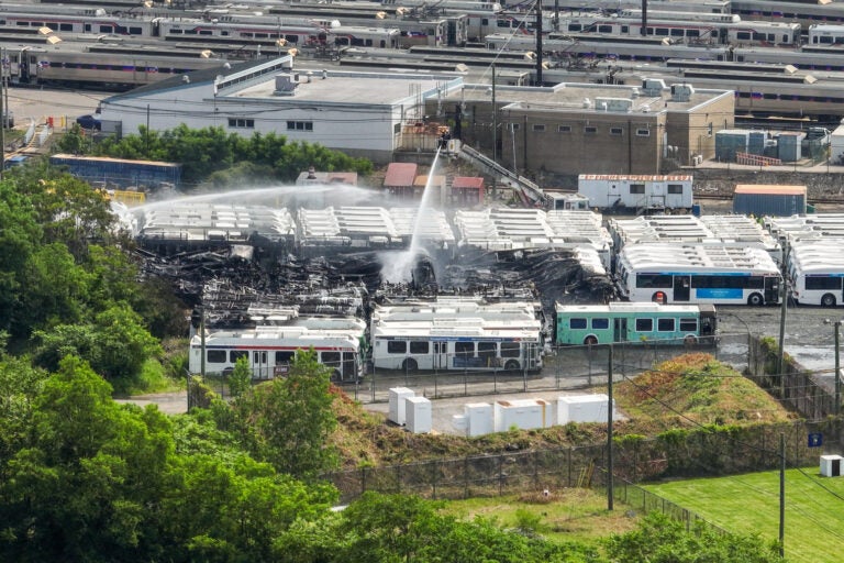 an aerial view of water being sprayed over the burned SEPTA buses