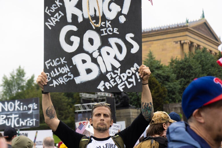 A Philadelphia Eagles fan protests at the No Kings rally on June 14, 2025. (Kimberly Paynter/WHYY)