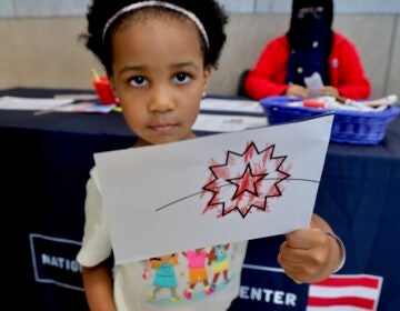A young girl holds up a flag she made
