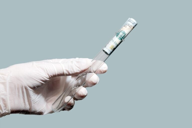 Laboratory Test Tube With A Hundred Dollar Bill Inside In The Left Male Hand. White Rubber Glove. Is If DNA testing companies can monetize consumer DNA, how much is your genetic data actually worth? (Bigstock/Romsvetnik)