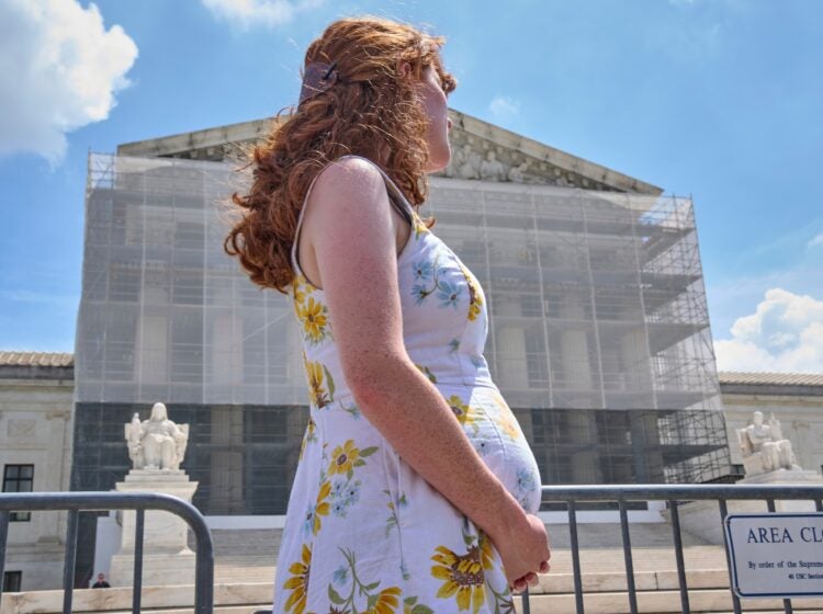 A pregnant U.S. citizen stands at a protest for birthright citizenship