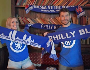 2 Chelsea fans hold up flags for their team