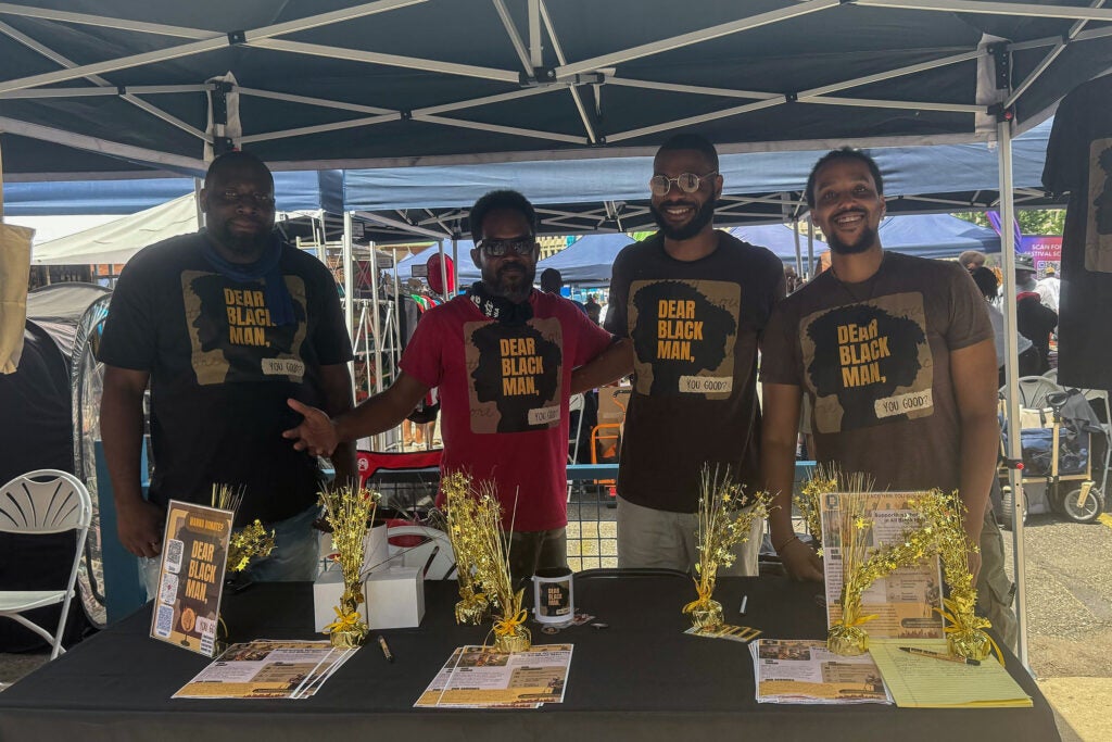 4 men posing for a photo behind a table at a booth