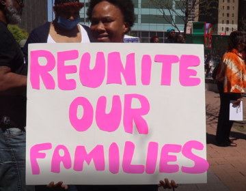 A woman holding up a sign that says 'Reunite our Families'