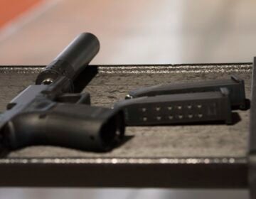 a gun with a silencer attached and two magazines lie on a table