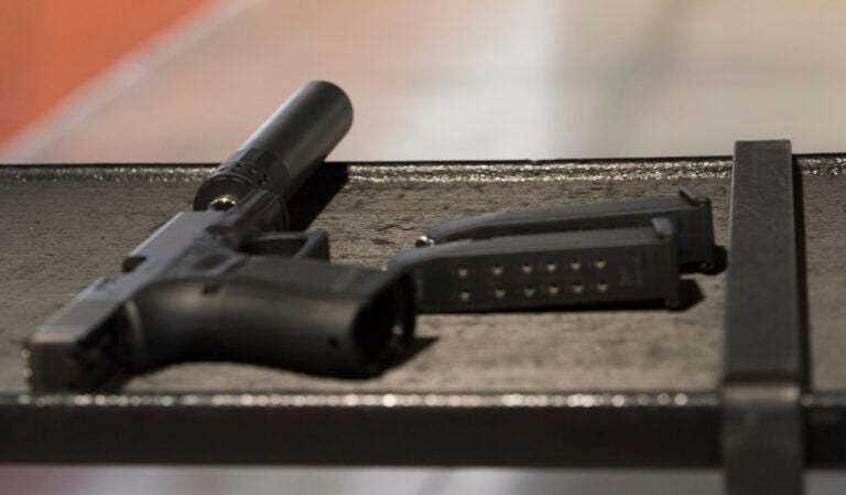 a gun with a silencer attached and two magazines lie on a table