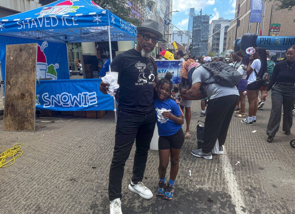 A man poses with his granddaughter at the block party