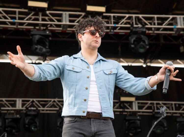 Adam Weiner on stage holding his hands up to the crowd