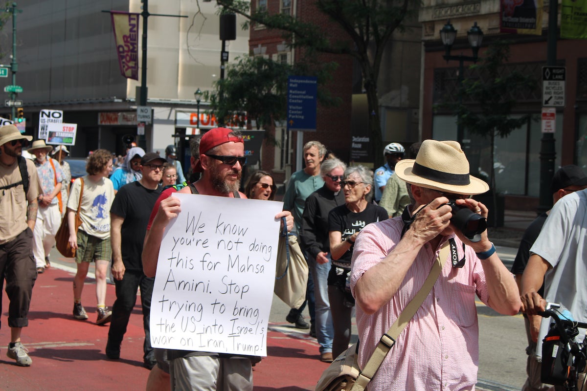 no-war-on-iran-2-copy A man holds a sign as people march in Philadelphia, calling for the U.S. to not become involved in the Israel-Iran war