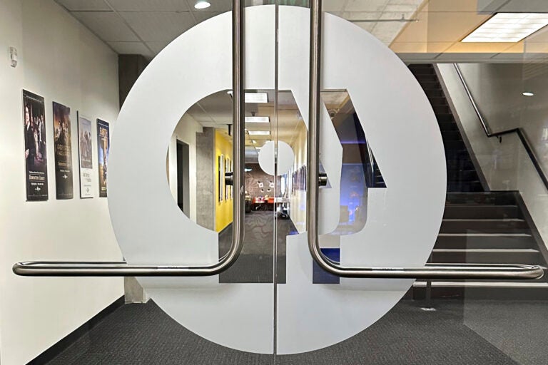Congress Budget Cuts Explainer The PBS logo is on interior double glass doors leading into an office