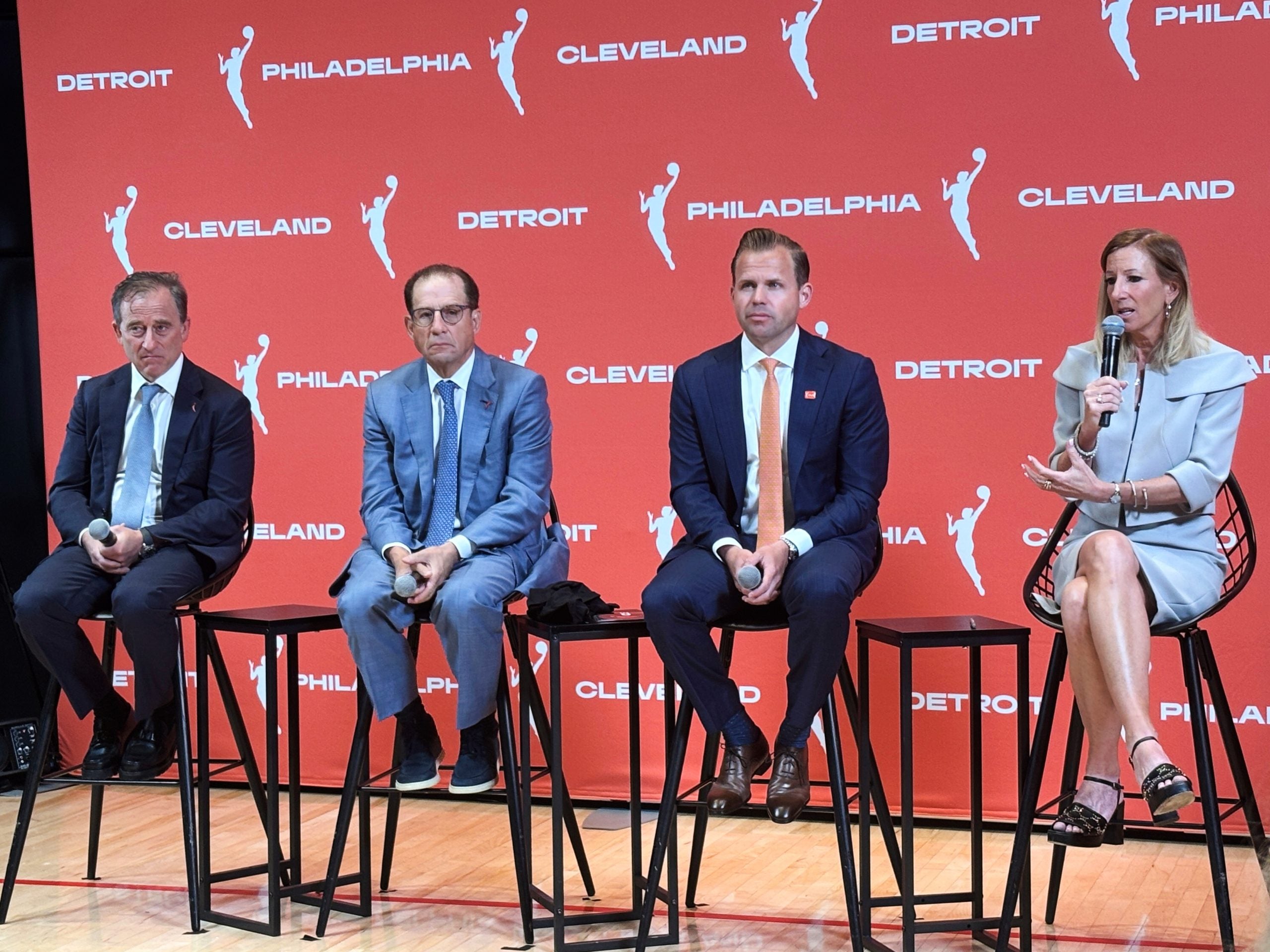 Various officials sitting on stools on a stage during a press conference