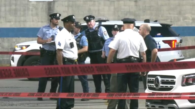 16968837_070525-wpvi-south-philly-mass-shooting-scene-img A group of Philadelphia police officers gather in a parking lot behind caution tape
