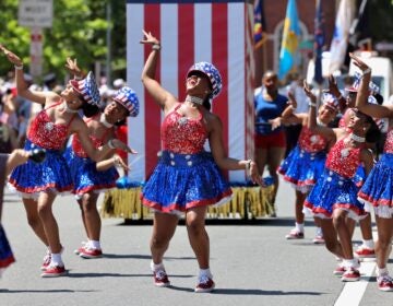 Women wearing American flag-themed dresses dance during the Philadelphia Fourth of July parade.