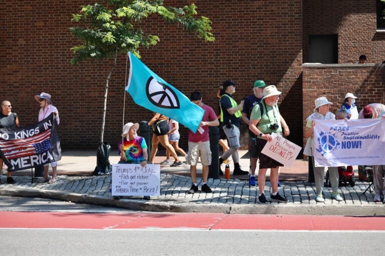 Anti-Trump protesters hold up various signs during the Fourth of July parade in Philadelphia.