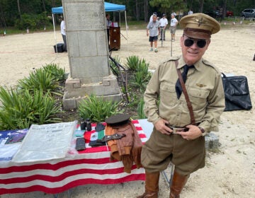 Actor Peter Titus stands next to items related to Emilio Carranza that he has collected while dressed like an fighter pilot from the era