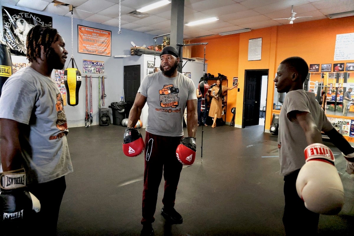 Champion boxer Michael Hilton (center) talks with Guns Down Gloves Up summer camp participants