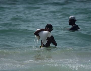 A Palestinian youth carries a sack of aid that landed in the Mediterranean Sea after being airdropped over central Gaza, at the shore of Zawaida, Gaza Strip Tuesday, July 29, 2025. (AP Photo/Abdel Kareem Hana)