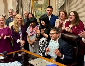 Matt Meyer holds up signed fiscal year 2026 budget legislation
