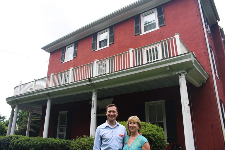 Hammerstein-birthday-2 A man and a woman smile at the camera outside a red house
