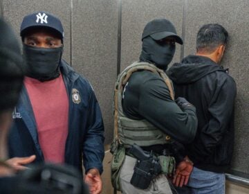 Immigration and Customs Enforcement agents escort a detained immigrant into an elevator