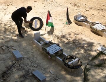 a man tidies the graves of Palestinian-American Sayfollah Musallet and Mohammed al-Shalabi