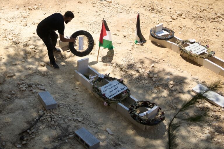 a man tidies the graves of Palestinian-American Sayfollah Musallet and Mohammed al-Shalabi