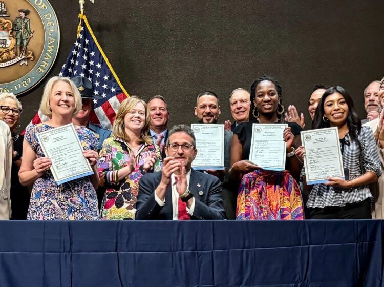 Delaware state lawmakers holding signed ICE bills