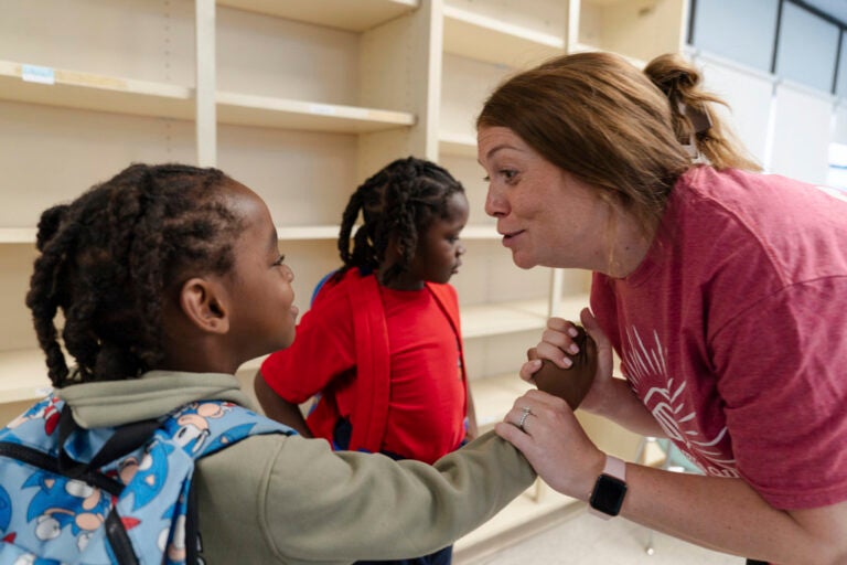 Trump Education Grant Freeze A teacher holds a student's hand