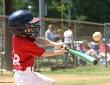 A child baseball player hits a ball with his bat