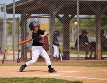 A Little League baseball player swings a bit