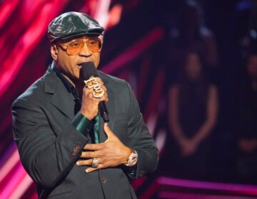 Rapper LL Cool J speaks into a microphone on stage at an awards ceremony