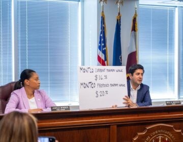 Montgomery County Commissioner Neil Makhija holds up a sign showing the previous starting minimum wage for county employees