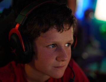A boy wearing headphones watches his video game intently