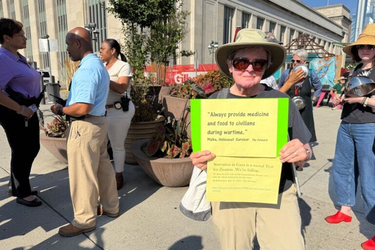 An activist holds a sign reading Always provide medicine and food to civilians during wartime, Malka, Holocaust Survivor, The Forward