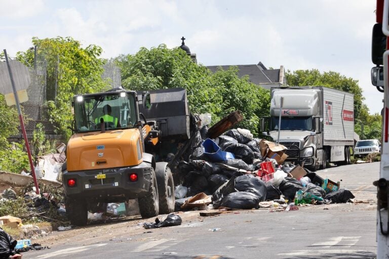 Non-union workers clear away mounds of trash