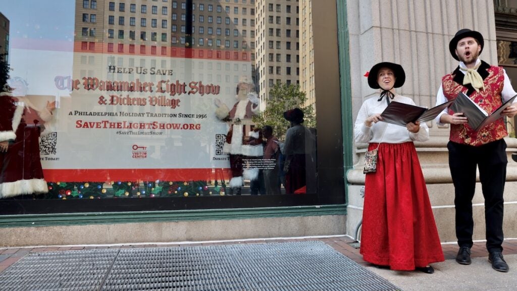 Characters from the Dickens Village sing carols outside the Wanamaker Building