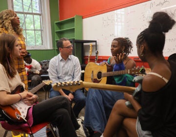 Pennsylvania Gov. Josh Shapiro listens as he sits with students holding guitars